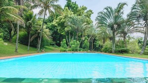 A clear blue swimming pool surrounded by lush greenery and palm trees. - Sitio em Indaiatuba com Piscina e Churrasqueira (Campinas)