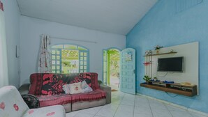 Una sala de estar con sofá, televisor montado en la pared y ventana con vistas al exterior.
