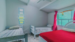 Una habitación con dos camas, una ventana con cortinas, un ventilador de techo y un interruptor de luz en la pared.