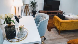 A modern living room with a white table, a blue armchair, a yellow sofa, a TV, and a potted plant. - Unparalleled Convenience | City View | Food Scene (Atlanta)