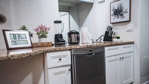 Eine Küche mit digitaler Uhr, Mixer, Kaffeemaschine und Geschirrspüler.
