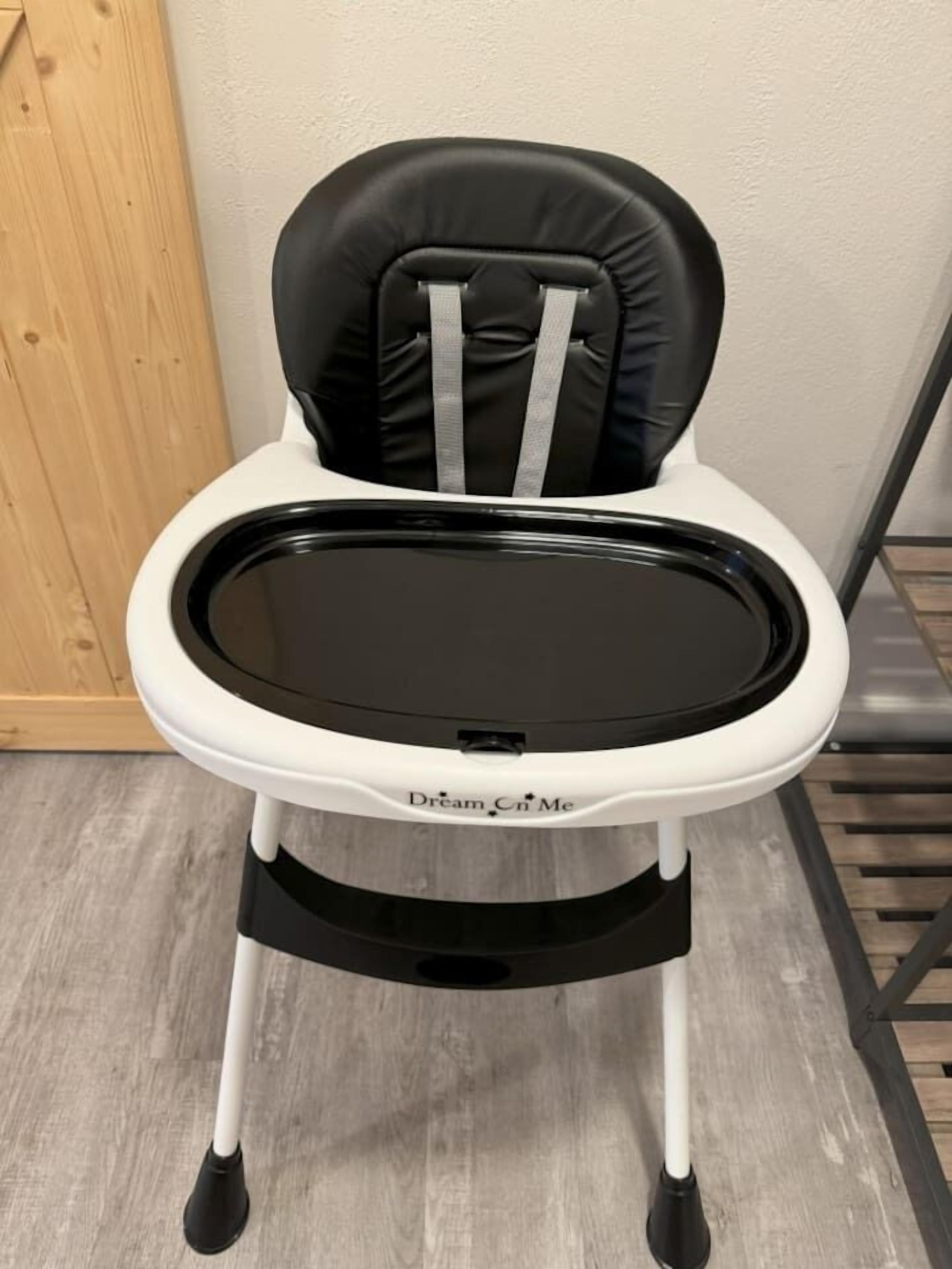 A black and white high chair with a tray, labeled "Dream Cn Me."