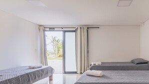 Habitación de hotel con una cama, una mesita pequeña y un ventanal corredero que da a un balcón.