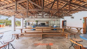 Un área exterior amplia con bancos y mesas de madera, un televisor y una cocina.