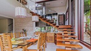 A modern dining area with a glass table, wooden chairs, and a wooden staircase. - Casa em São Sebastião com Piscina, Jacuzzi e Vista (São Sebastião)