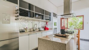 A modern kitchen with stainless steel appliances, a tiled backsplash, and a window with a view of greenery. - Casa em São Sebastião com Piscina, Jacuzzi e Vista (São Sebastião)