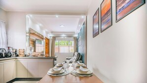 A modern kitchen with a dining area, a coffee machine, and a large window. - Casa em Itanhaém com piscina 5 min de carro da Praia (Itanhaém)