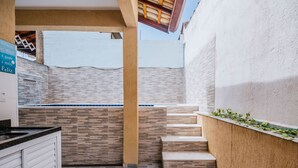 A modern kitchen with a tiled backsplash, a wooden counter, and a built-in stove. - Casa em Itanhaém com piscina 5 min de carro da Praia (Itanhaém)