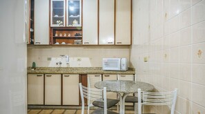 A compact kitchen with a granite countertop, a microwave, and a small dining table with chairs.