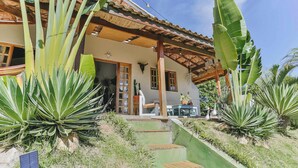 A house with a porch, large plants, and a solar panel. - Casa em Mairinque em meio a Natureza com Piscina (Mairinque)