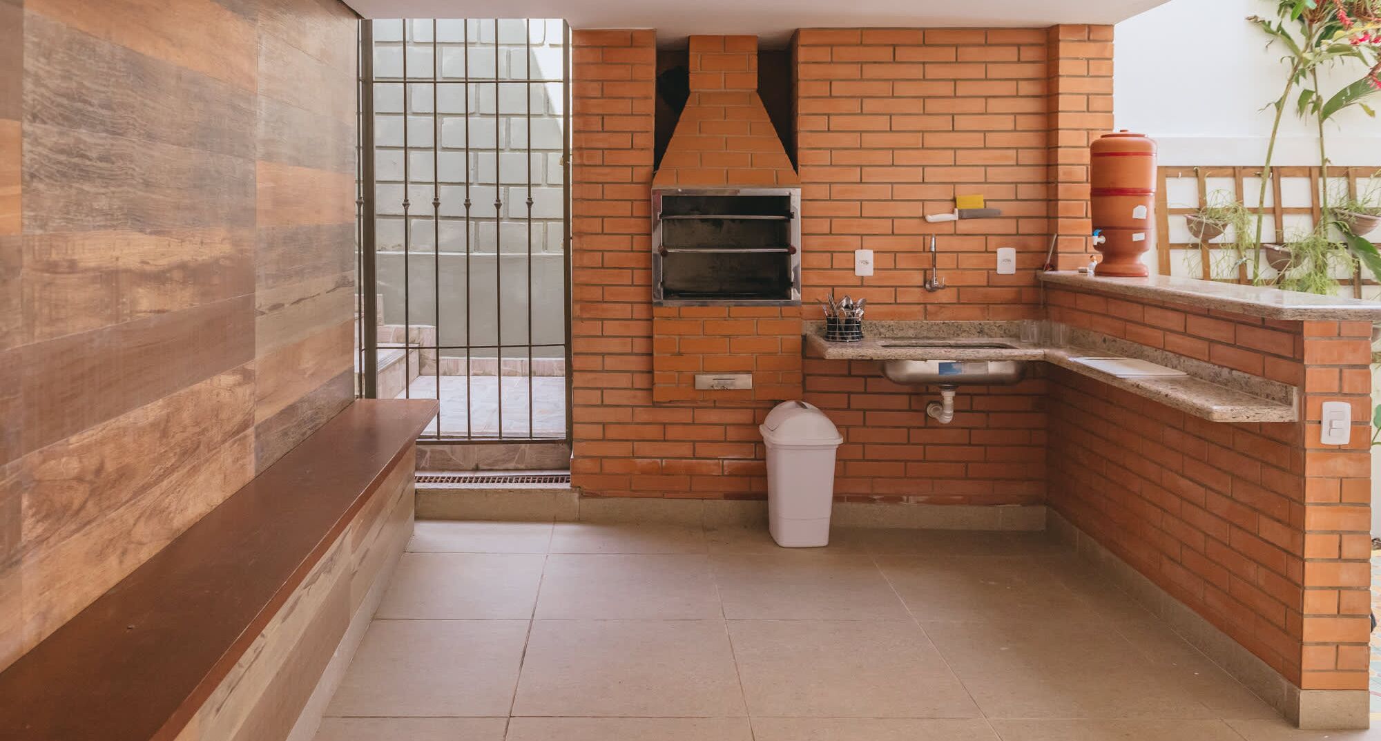A compact kitchen with a built-in oven, sink, and a small trash bin.