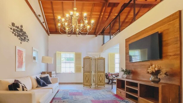 Una sala de estar con candelabro, un sofá, un televisor montado en la pared y un aparador decorativo.