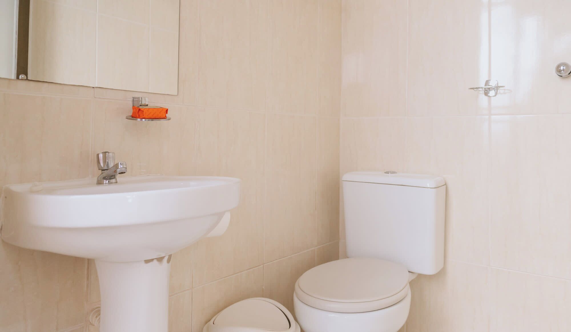 Une salle de bain avec un lavabo blanc, des toilettes et un miroir.