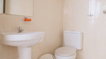 Une salle de bain avec un lavabo blanc, des toilettes et un miroir.