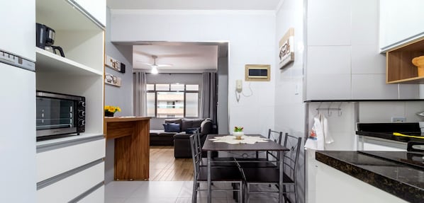 Eine moderne Küche mit Backofen, ein Essbereich mit Tisch und Stühlen sowie ein Wohnzimmer mit Sofa und Kaffeemaschine.