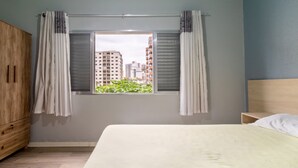 Un dormitorio con cama, armario de madera y ventana con cortinas.