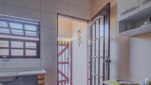 A bathroom with a window, a door, and a shelf with items. - Casa em São Sebastião a 5 min da Praia (São Sebastião)
