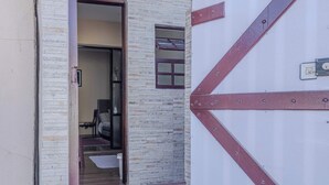 A doorway leading to a room with a bed, a small window, and a door with a metal handle. - Casa em São Sebastião a 5 min da Praia (São Sebastião)