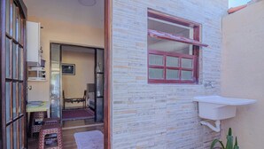 A small room with a tiled wall, a window with a red frame, a white sink, and a potted plant. - Casa em São Sebastião a 5 min da Praia (São Sebastião)