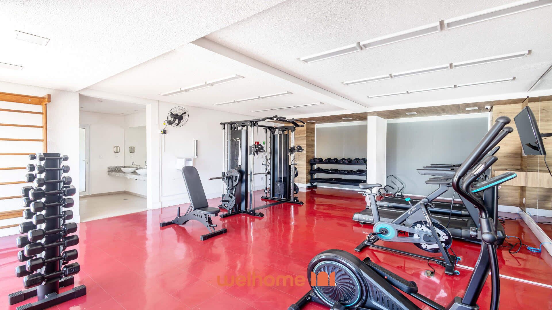Un gimnasio moderno con diversos equipos de ejercicio, incluyendo pesas, una prensa de banca y máquinas de cardio.