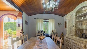 Un comedor con mesa de madera, mantel de encaje y una araña.