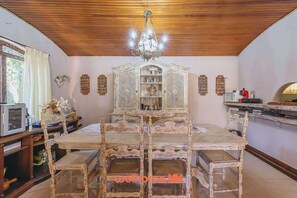 Un comedor con techo de madera, una araña, un aparador grande y ornamentado, y una mesa de comedor con sillas.