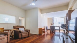 A spacious living area with a wooden floor, a sofa, a coffee table, and a TV.