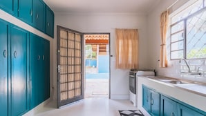Une cuisine avec des armoires de couleur turquoise, un fourneau et un évier.