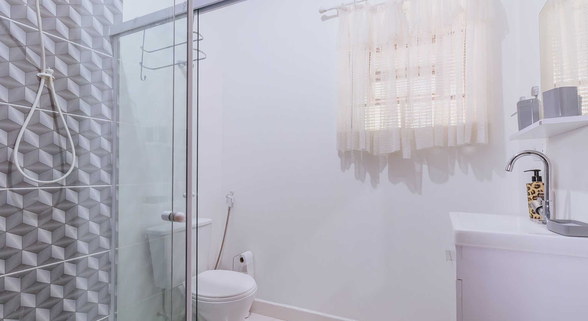 Un baño moderno con cabina de ducha de vidrio, inodoro y lavamanos con grifo.
