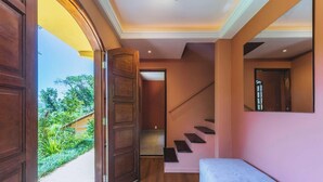 Un pasillo con puerta de madera, escalera y un banco.