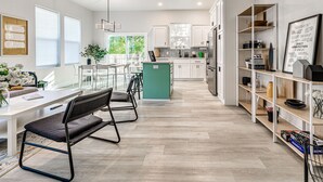 Une cuisine moderne avec des meubles blancs, un îlot central et un coin repas comprenant des chaises et une table.