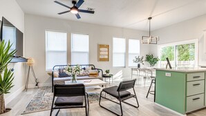 Un appartement moderne comprenant un coin repas, une cuisine et une grande fenêtre laissant entrer la lumière naturelle.