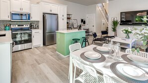 Une cuisine moderne avec des armoires blanches, des appareils en acier inoxydable et un îlot central vert.