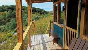 A wooden deck with a bench and a view of a forested landscape.