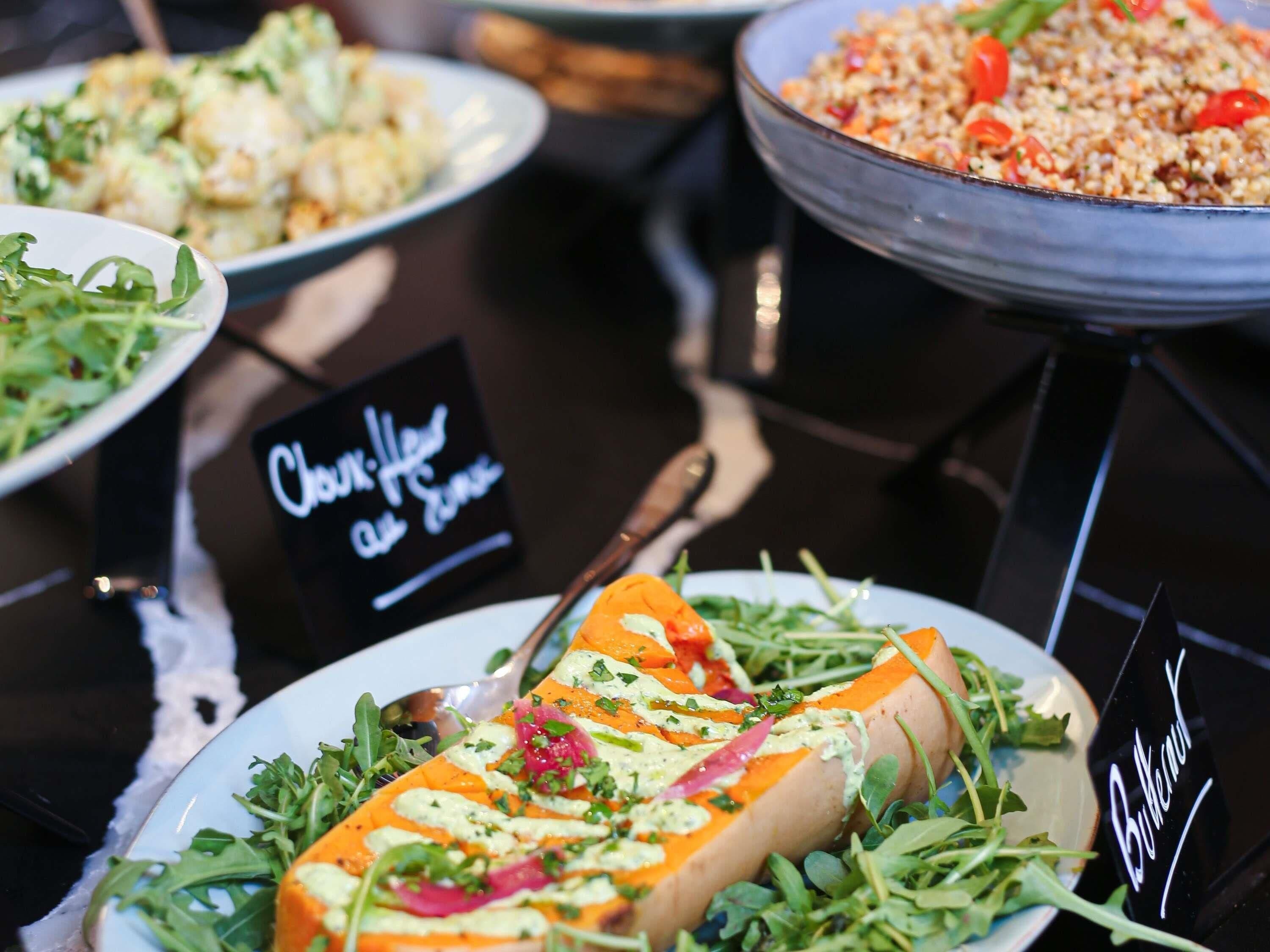 Un bufé con diversos platos, incluyendo un plato de salmón y vegetales, y un cartel que dice 'Elección del Chef'.