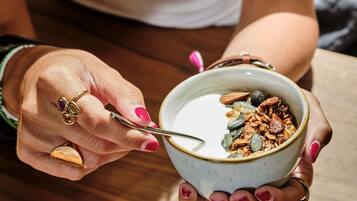 Iemand houdt een kom yoghurt met granola en zaden vast.