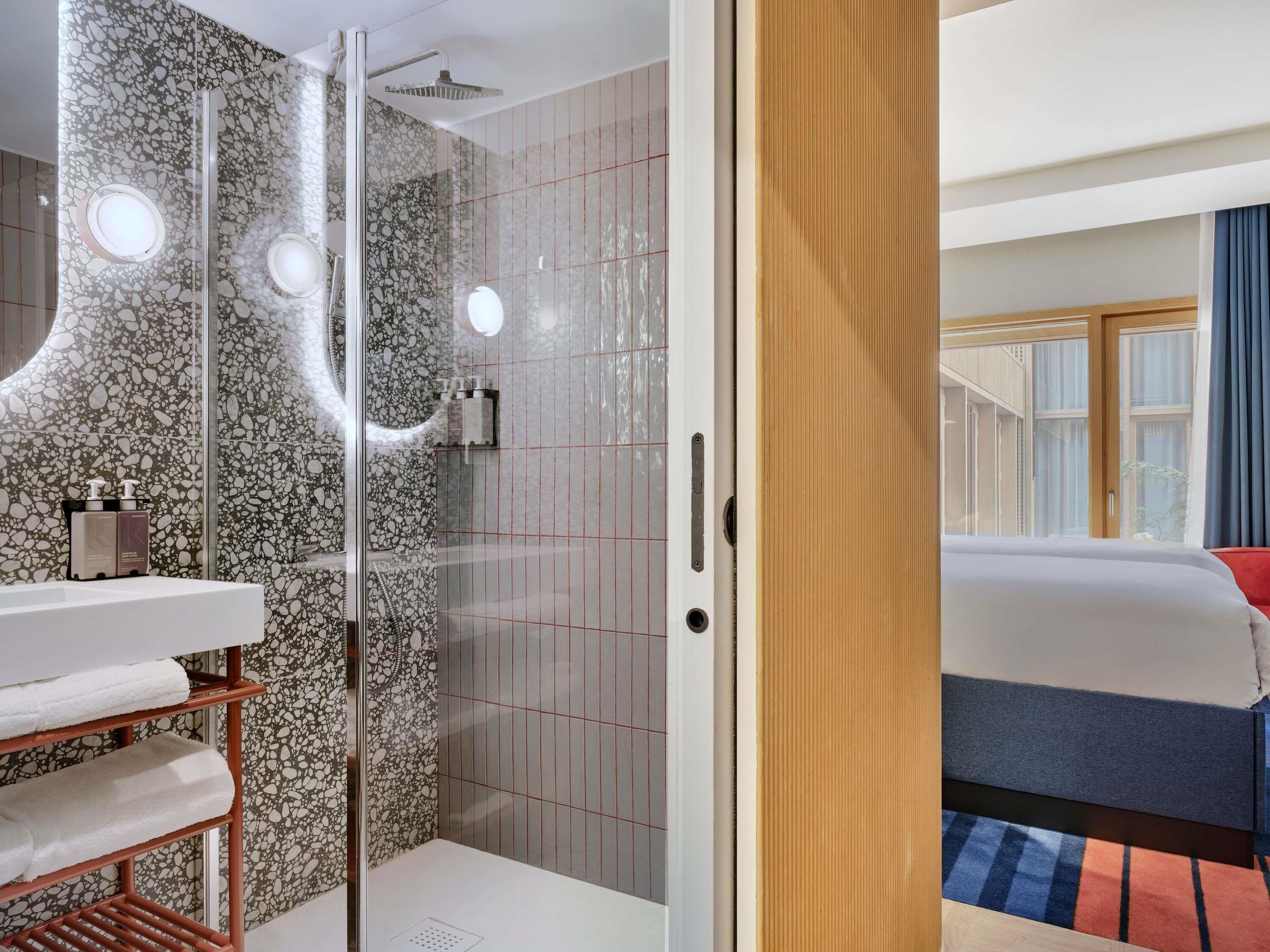Un bagno moderno con cabina doccia in vetro, un lavandino bianco e un porta asciugamani.
