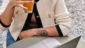 Una persona sentada a una mesa con una computadora portátil y sosteniendo un vaso de líquido ámbar.