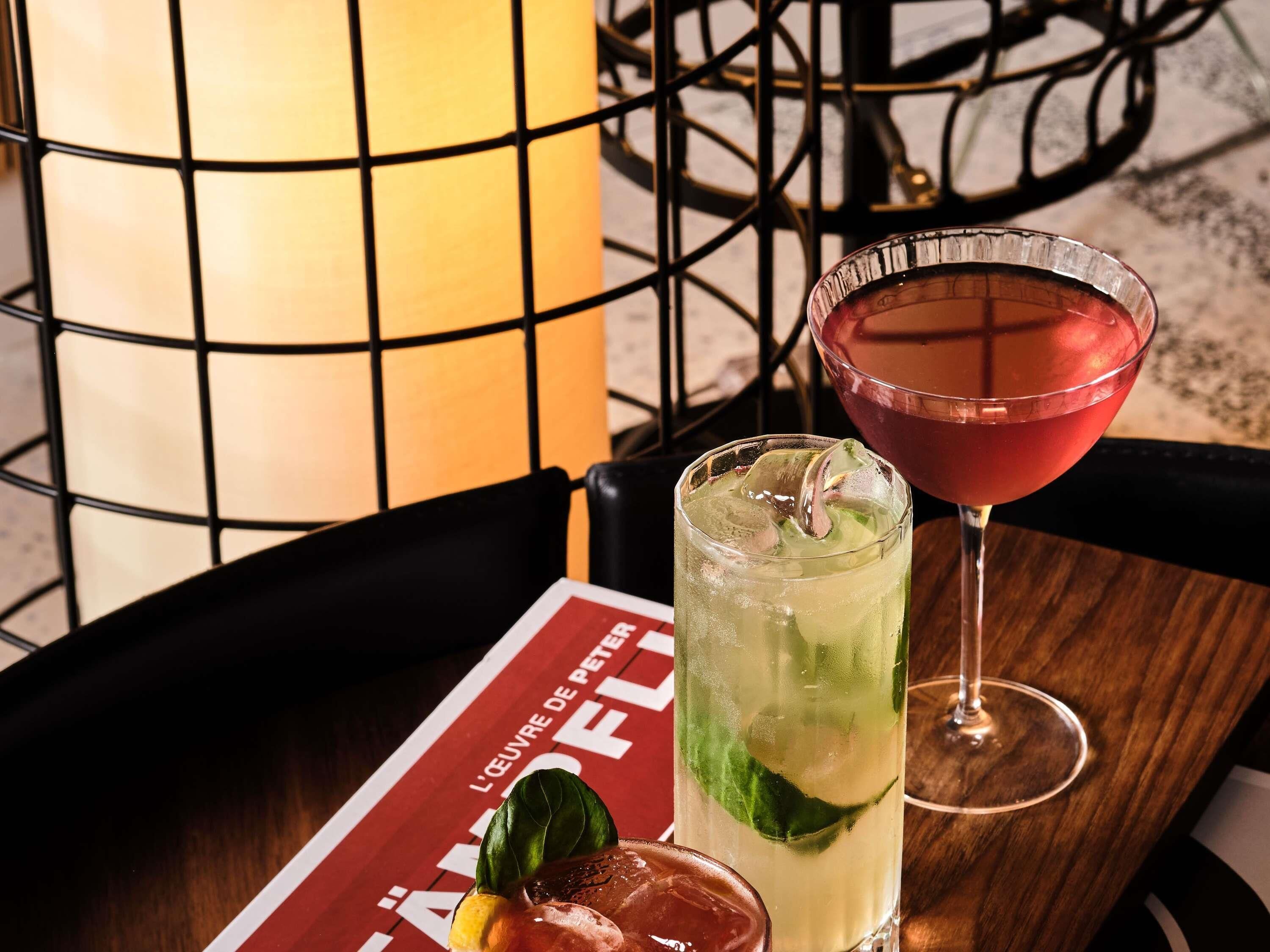 Una mesa con dos bebidas, un menú y una lámpara.
