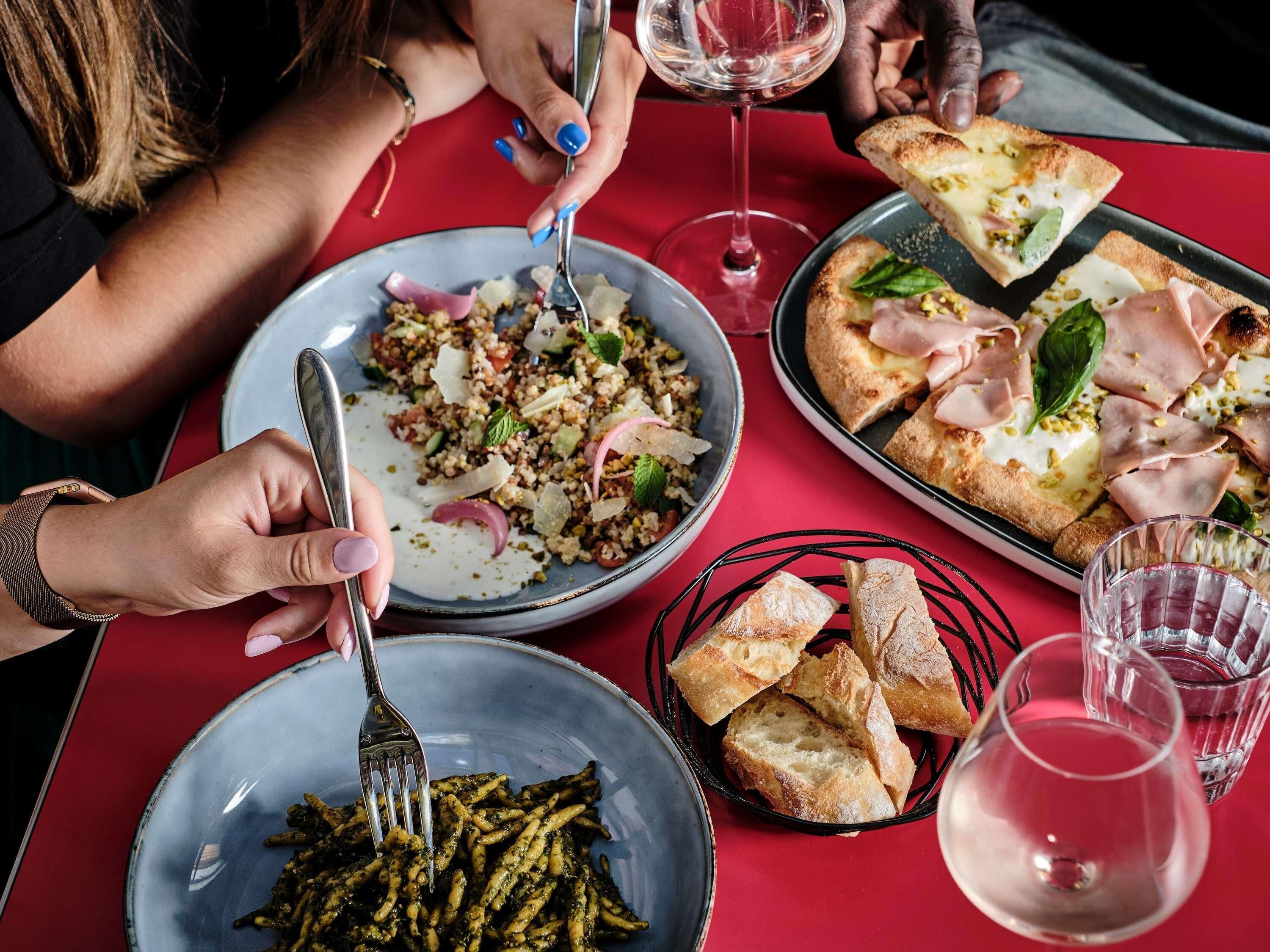 Une table à manger avec différents plats, notamment des pâtes, des pizzas et du pain.