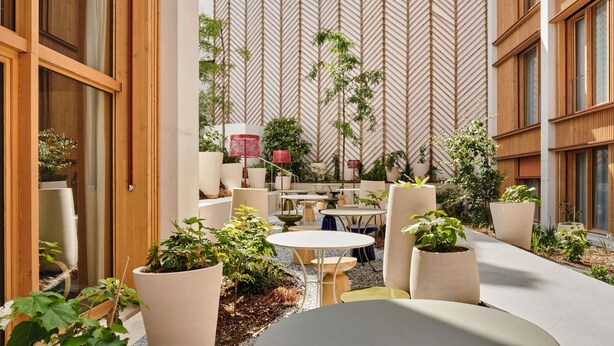 A courtyard with outdoor seating, potted plants, and a patterned wall. - TRIBE Paris Pantin (Pantin)