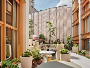 A courtyard with outdoor seating, potted plants, and a patterned wall. - TRIBE Paris Pantin (Pantin)