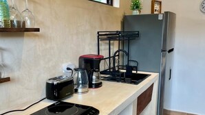 A modern kitchen with a built-in induction cooktop, a coffee maker, and a refrigerator. - Modern and charming apartment with pool Punta Sur (Isla Mujeres)