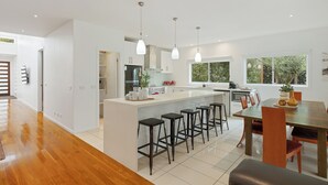 A modern kitchen with a central island, bar stools, and pendant lighting.