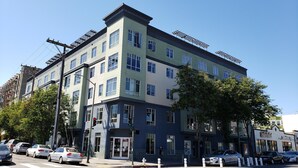A multi-story building with a mix of residential and commercial spaces, including a visible storefront. - Live Close to Everything! (Oakland)