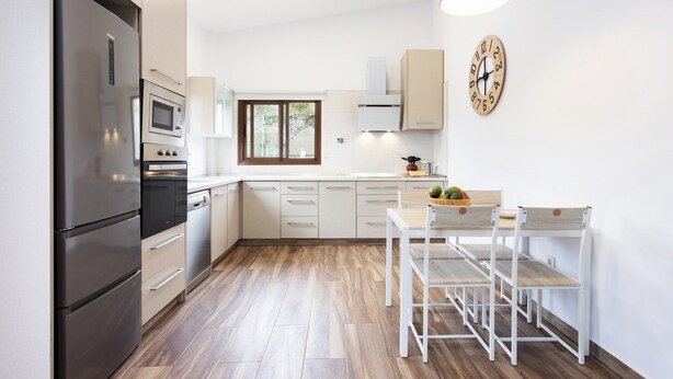 Una cocina moderna con refrigerador, horno, microondas y un comedor con mesa y sillas.