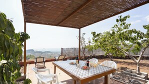 Un patio al aire libre con mesa y sillas, vistas al paisaje y una estructura de pérgola.