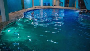 An indoor swimming pool with clear blue water, a diving board, and a blue wall. - Pacific Paradise (Champerico)