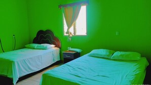 A room with two single beds, a nightstand, and a window with curtains. - Pacific Paradise (Champerico)
