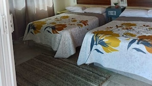 Un dormitorio con dos camas, un ventilador de techo, una mesita de noche y una lámpara en la pared.